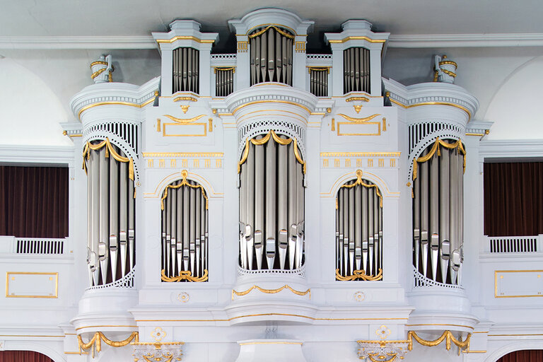 weiße Orgel mit silbernen Orgelpfeifen, hoch oben unter der Decke