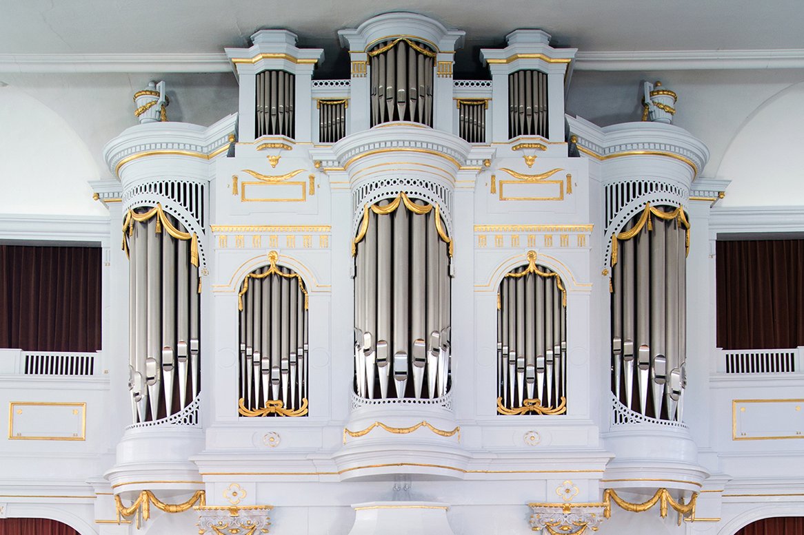 weiße Orgel mit silbernen Orgelpfeifen, hoch oben unter der Decke
